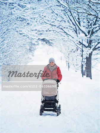 Lächelnd Mutter Wandern mit Kinderwagen in Winterlandschaft