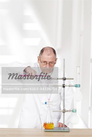 Scientist pouring chemical into beaker in laboratory