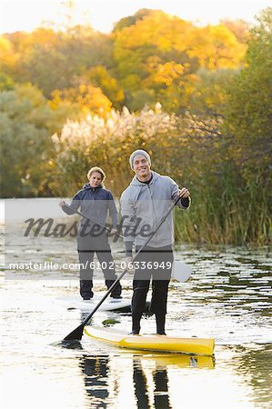 Two people smiling on paddle boards on river