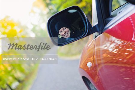 Woman smiling in rear view mirror on country road