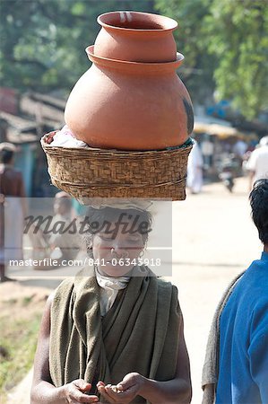 Dunguria Kondh woman with tribal noserings carrying terracotta pots in a basket on her head, Bissam Cuttack, Orissa, India, Asia