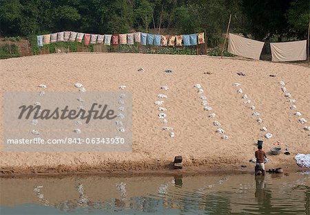 Dhobi wallah, laver le linge dans la rivière avec des piles très organisées de lavage blanc disposées sur le sable, Raghurajpur, Orissa, Inde, Asie