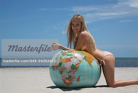 Woman in bikini leaning on globe