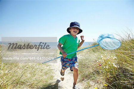 Boy carrying fishing net on beach