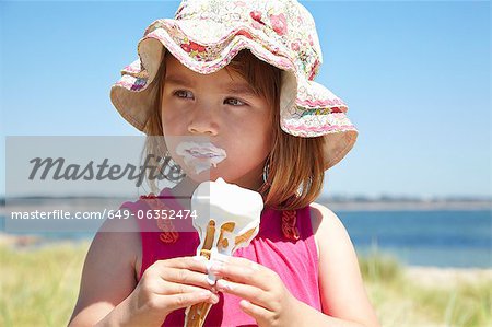 Fille de manger la crème glacée sur la plage