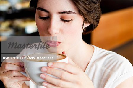 Femme soufflant sur le café dans le café
