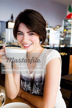 Smiling woman drinking coffee in cafe