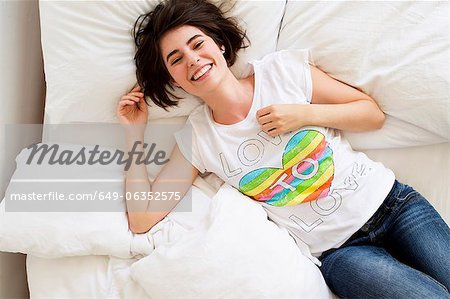 Femme souriante reposante sur le lit