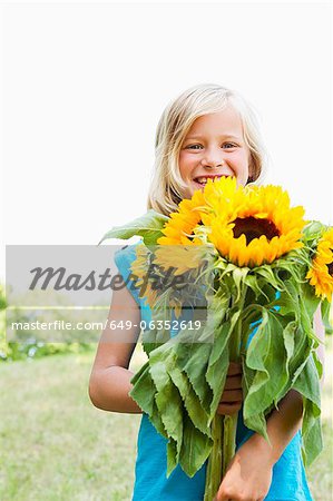 Jeune fille souriante transportant des tournesols