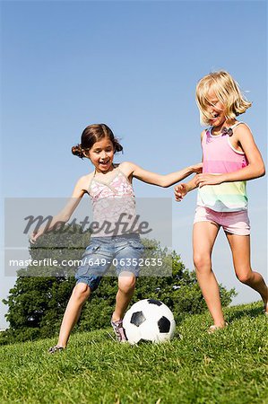 Girls playing soccer in field