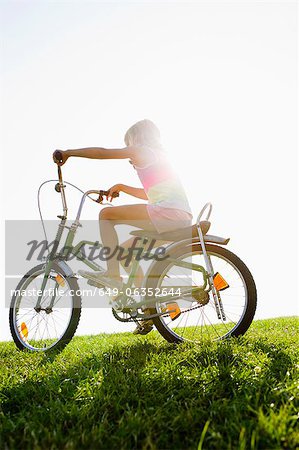 Girl riding bicycle in grass