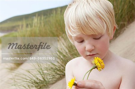 Boy holding flowers on sand dune