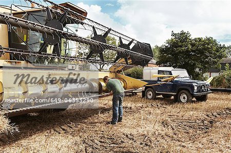 Farmer examining thresher on farm