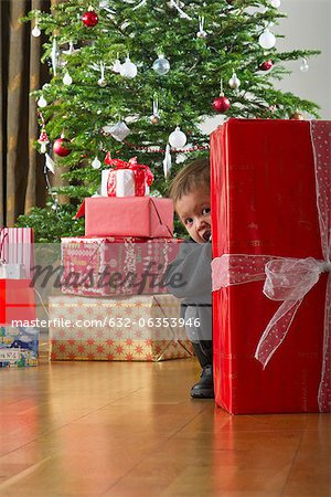 Baby girl hiding behind Christmas present