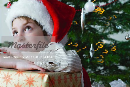 Boy resting head on Christmas present, daydreaming