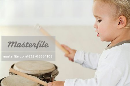 Baby boy playing drums, side view
