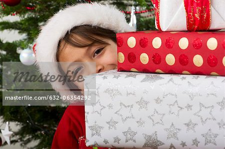 Junge spähen um Stapel von Weihnachten präsentiert