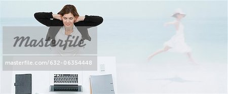 Reife geschäftsfrau am Schreibtisch sitzend vorstellen, selbst am Strand