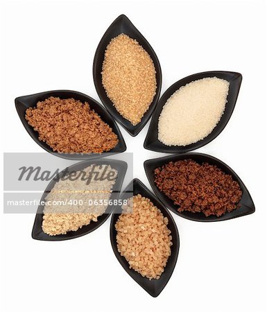 Selection of demarara, granulated, molasses, muscovado, crystal and light brown sugar in black leaf shaped dishes over white background.
