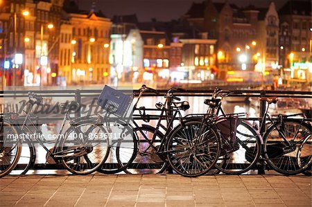 Bikes parked on a bridge at night in Amsterdam