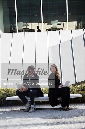 Business People with Laptops Sitting on Bench