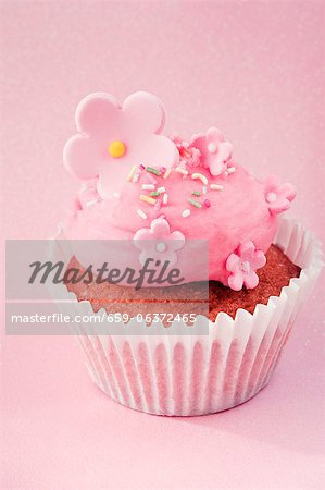 A cupcake decorated with pink cream and sugar flowers