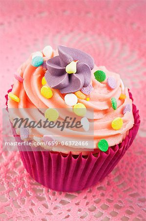 A cupcake decorated with buttercream, sugar sprinkles and a sugar flower