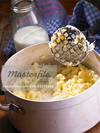 Mashed potatoes and a masher in a pot