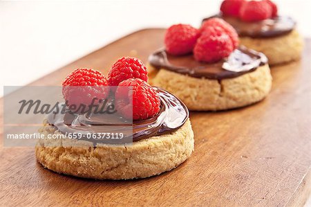 Biscuits de sablé avec propagation de chocolat aux noisettes et framboises ; Sur une planche à découper Biscuits de sablé avec propagation de chocolat aux noisettes et framboises ; Sur une planche à découper