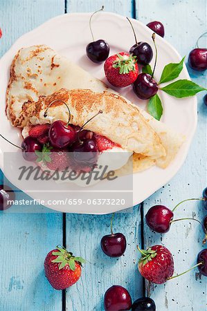 A crepe with vanilla cream, cherries and strawberries