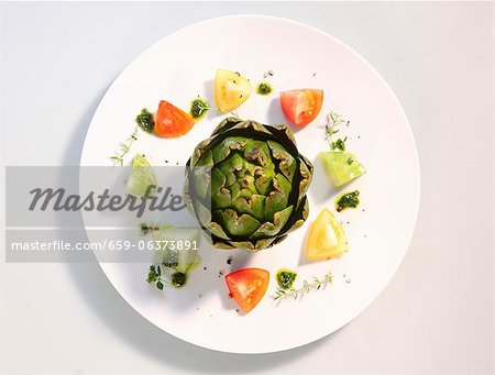 An artichoke with tomatoes and pesto