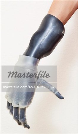 Close-up of man's prosthetic hand over gray background