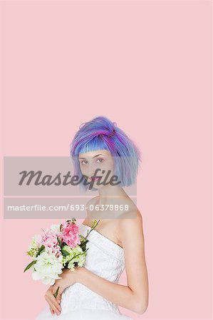 Portrait d'une belle jeune femme en robe de mariée avec des cheveux colorés sur fond rose