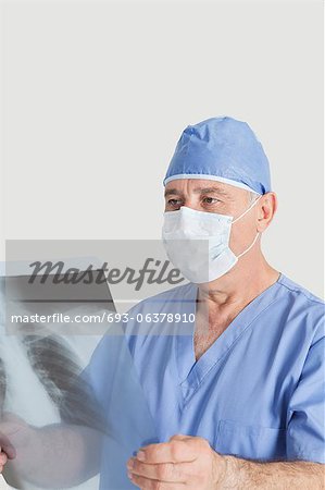 Leitende männlich Chirurg untersuchen Röntgen über den grauen Hintergrund