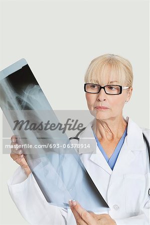 Weiblichen Oberarzt untersuchen Röntgen über den grauen Hintergrund