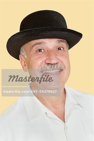 Portrait of happy senior man with black hat over yellow background
