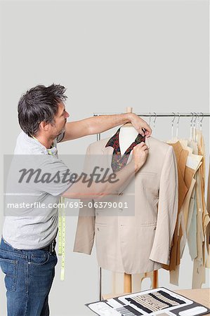 Male dressmaker adjusting suit on tailor's dummy in design studio