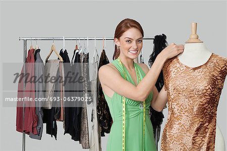 Portrait of beautiful female fashion designer adjusting cloth on tailor's dummy