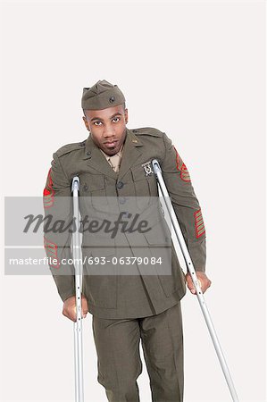 Portrait of African American military officer with crutches, studio shot on gray background