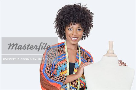 Portrait of African American female fashion designer with tailor's dummy over gray background
