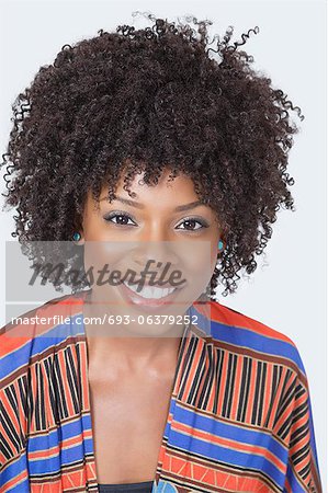 Portrait of pretty African American woman in traditional wear smiling over gray background