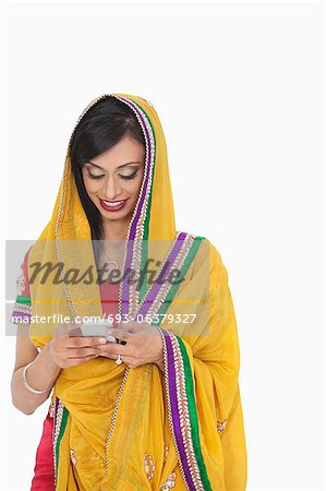 Femme indienne en vêtements traditionnels à l'aide de téléphone portable sur fond blanc