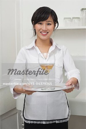 Portrait of female housekeeper serving wine in goblet