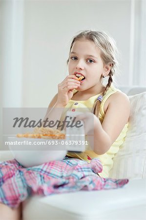 Kleines Mädchen vor dem Fernseher wie sie Rad Form Snack-Pellets isst