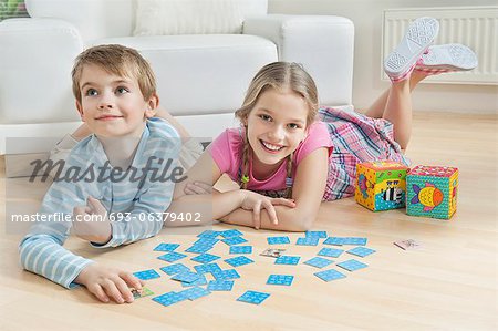 Portrait d'une fille et un petit frère gisant sur le sol avec des cartes
