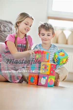 Children stacking blocks while sitting on floor Children stacking blocks while sitting on floor