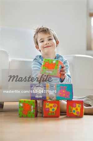 Portrait de mignon petit garçon empiler les blocs tout en étant assis sur le plancher