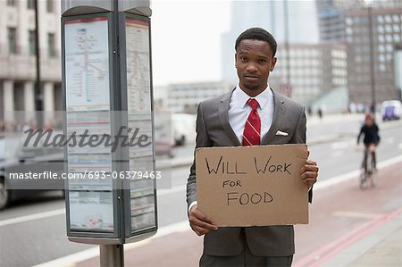 Young businessman holding "Will Work for Food" sign at street