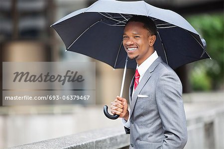 Glücklich Afroamerikaner Unternehmer holding Regenschirm