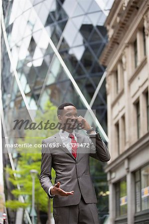 Happy businessman using cell phone outside building